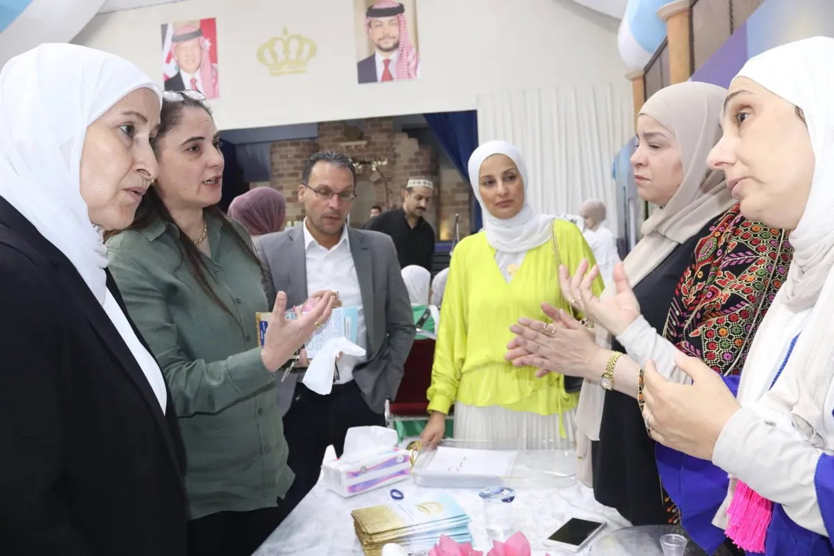 نقاش بين الحضور حول طاولة تضم مواد تعريفية في إحدى مشاركات الجمعية